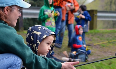 A mom helps her daughter hold a fishing pole at Canby Pond.