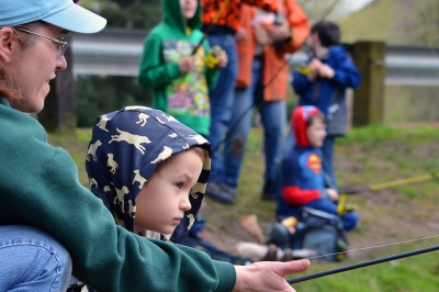 A mom helps her daughter hold a fishing pole at Canby Pond.